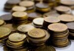 Stacks of gold and silver coins representing precious metals markets reacting to Fed Chair Kevin Warsh's inflation-focused policy outlook